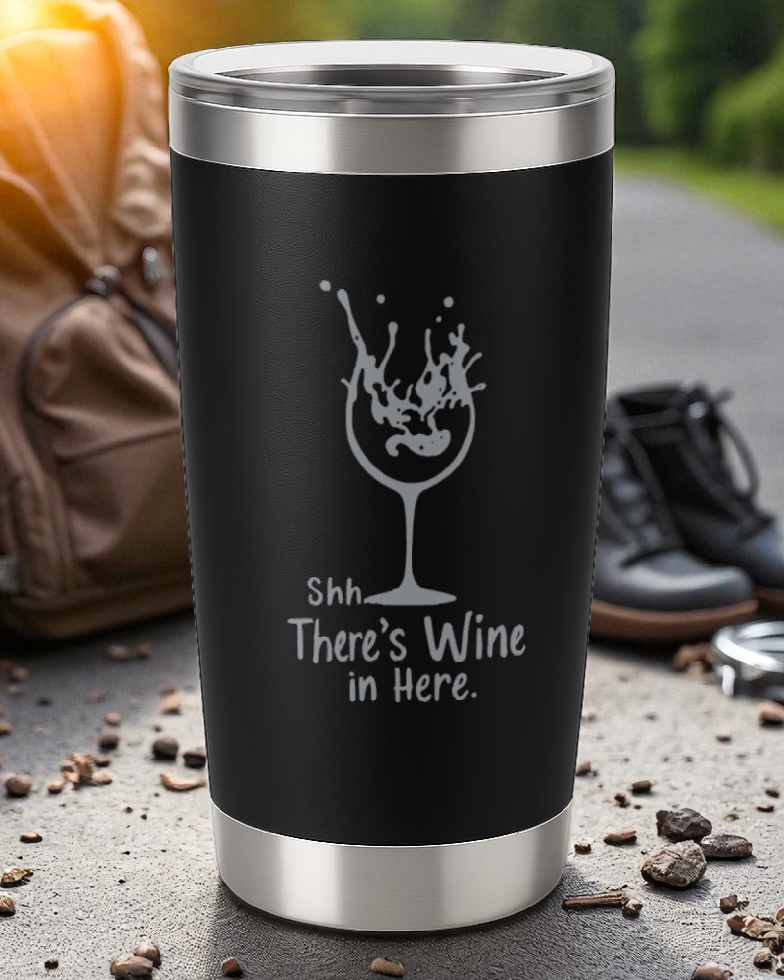 20oz black stainless steel tumbler with laser-engraved "Shhh… There’s Wine in Here" text and wine glass design, spill-resistant with clear lid.