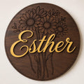 Custom floral name sign with engraved flowers and raised lettering on round wood wall decor