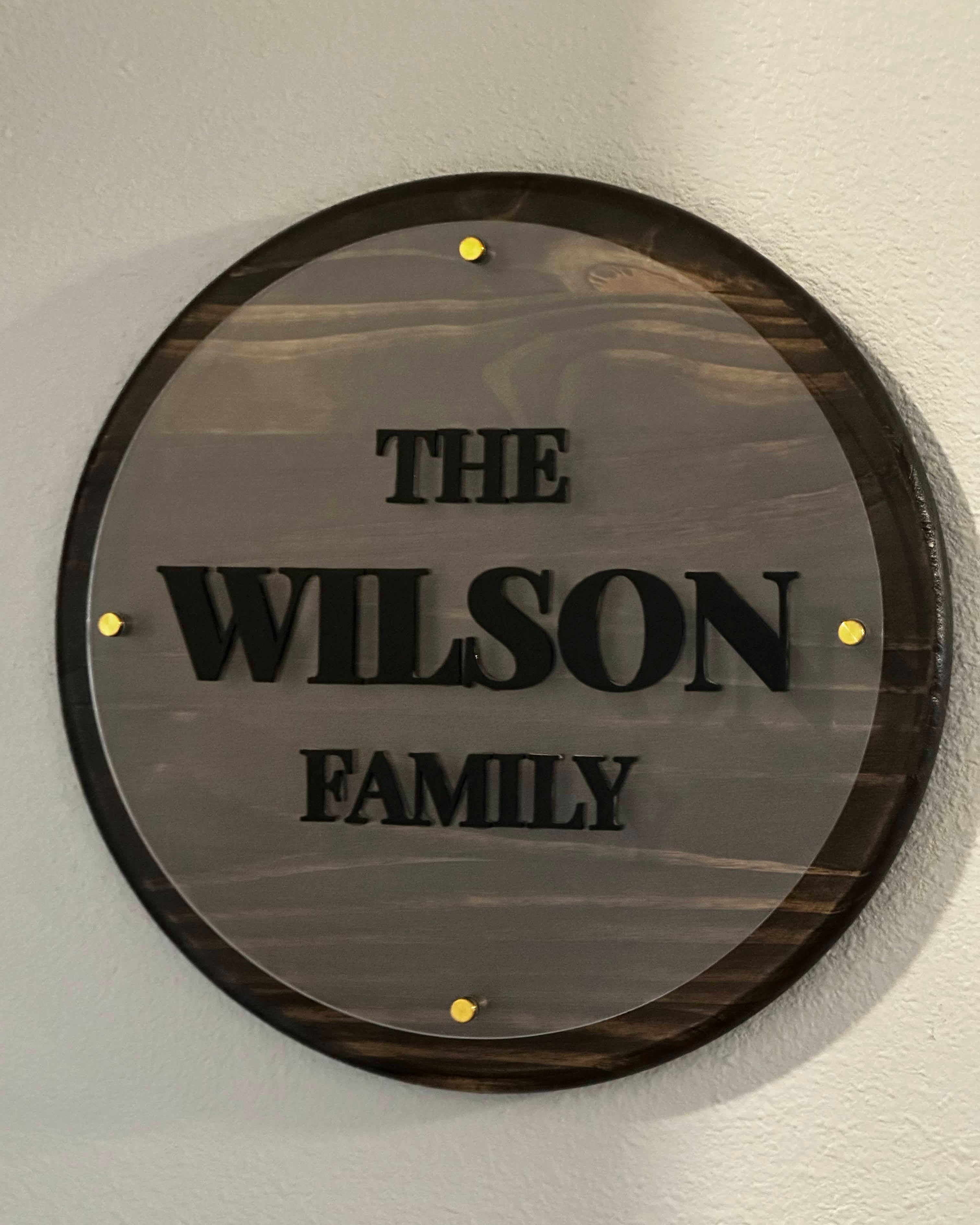 Round decorative plaque with 'The Wilson Family' engraving on a light gray wall.