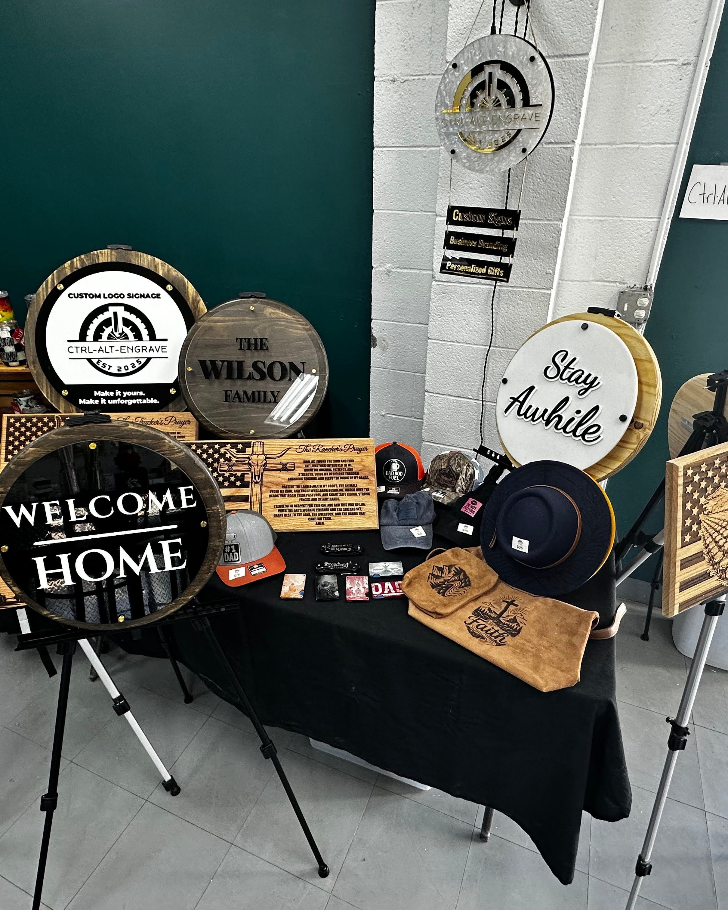 Collection of decorative signs on a table with a dark green wall and white brick accents in the background.