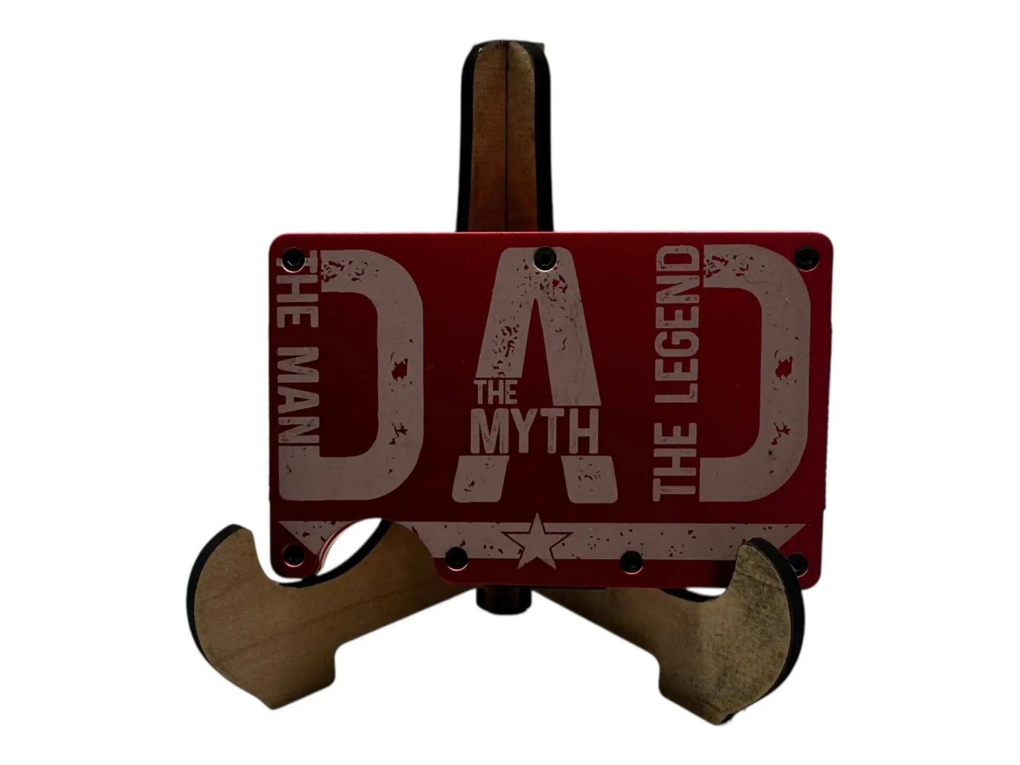 Engraved metal money clip wallet in red, featuring "Dad The Man The Myth The Legend" design, displayed on a wooden stand.
