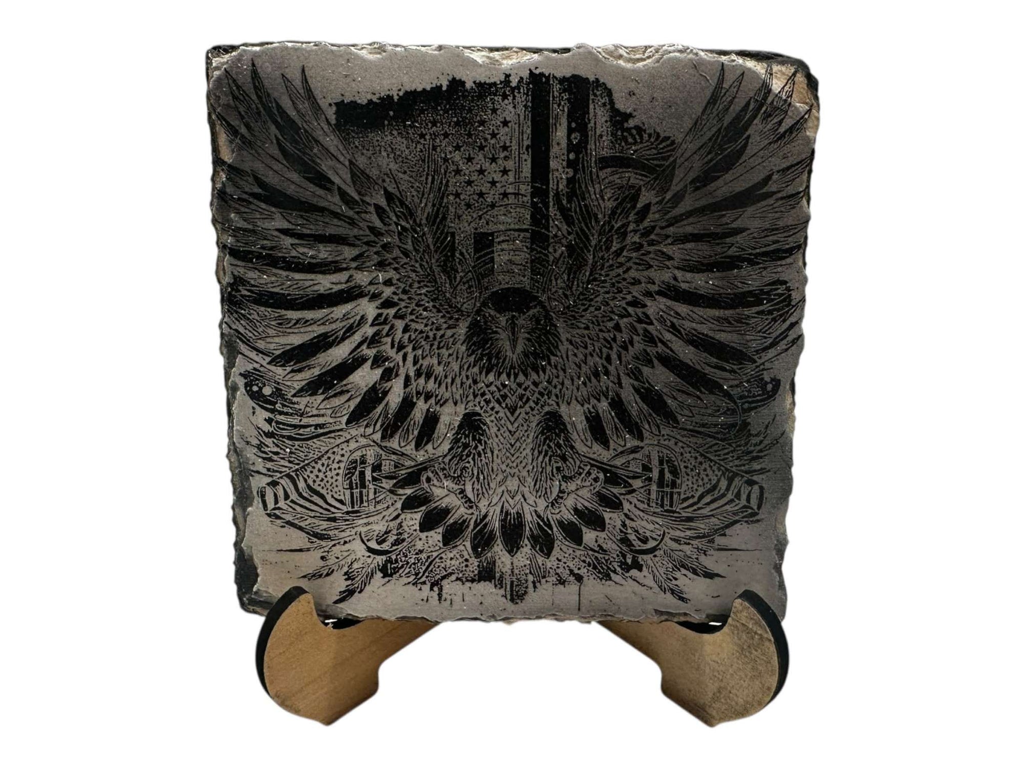 Hand-painted slate coaster with intricate greyscale eagle design in black and white on a wooden stand.