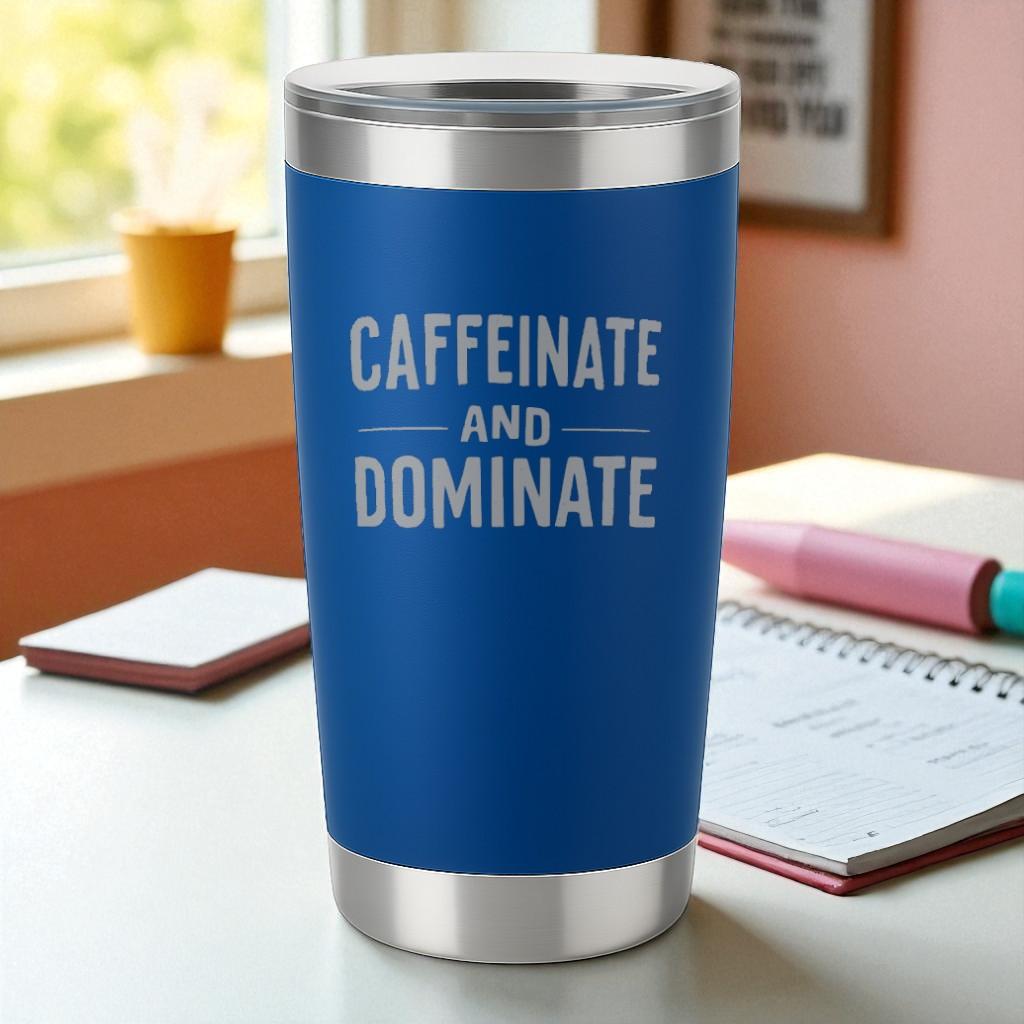 Blue 20oz stainless steel tumbler with laser-engraved "Caffeinate and Dominate" text and clear lid on desk.