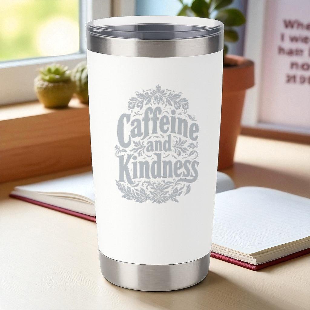 20oz white powder-coated insulated tumbler with "Caffeine and Kindness" laser-engraved design and clear lid on desk near window
