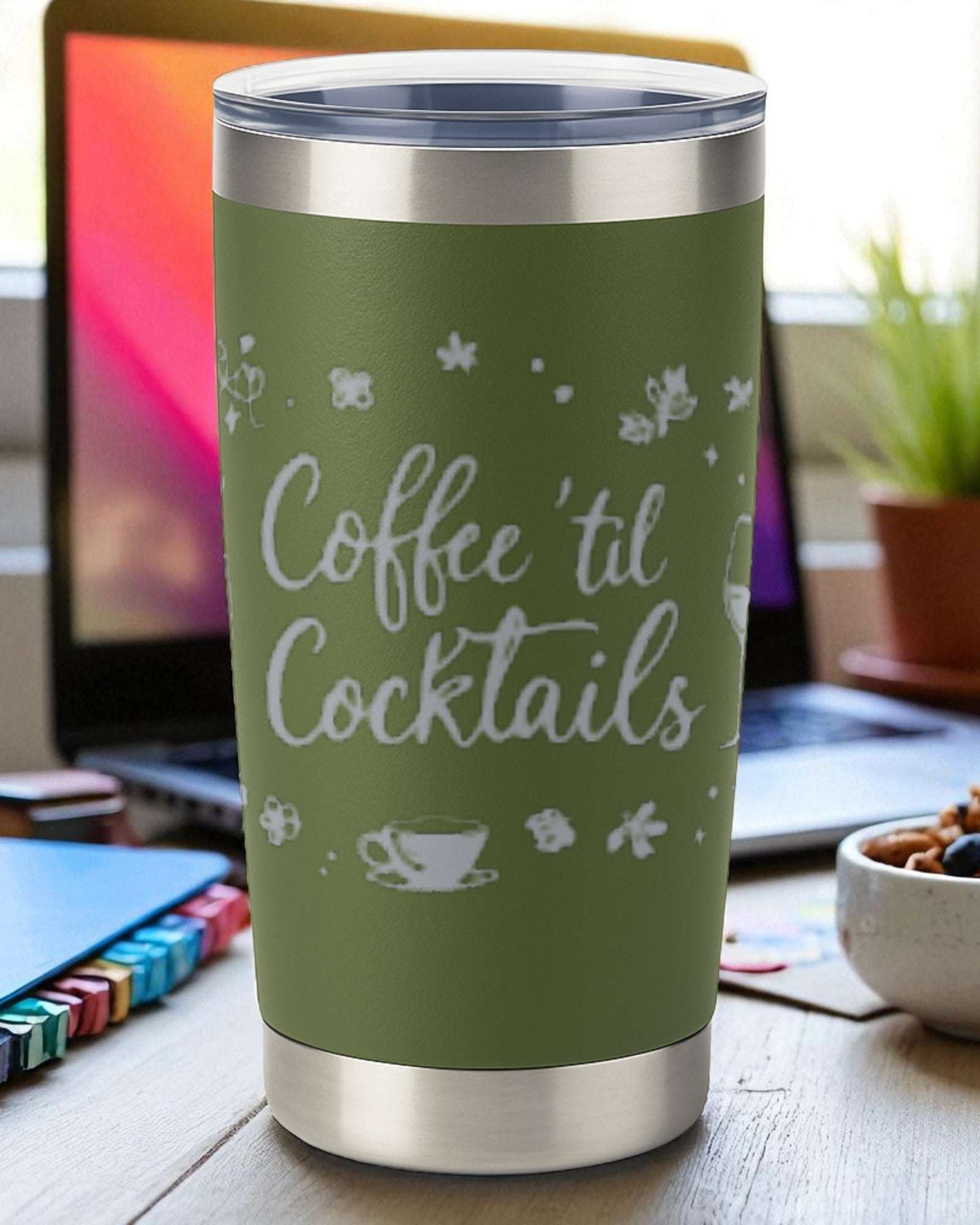 20oz green insulated stainless steel tumbler engraved with "Coffee 'Til Cocktails" and clear lid on wooden desk with laptop in background