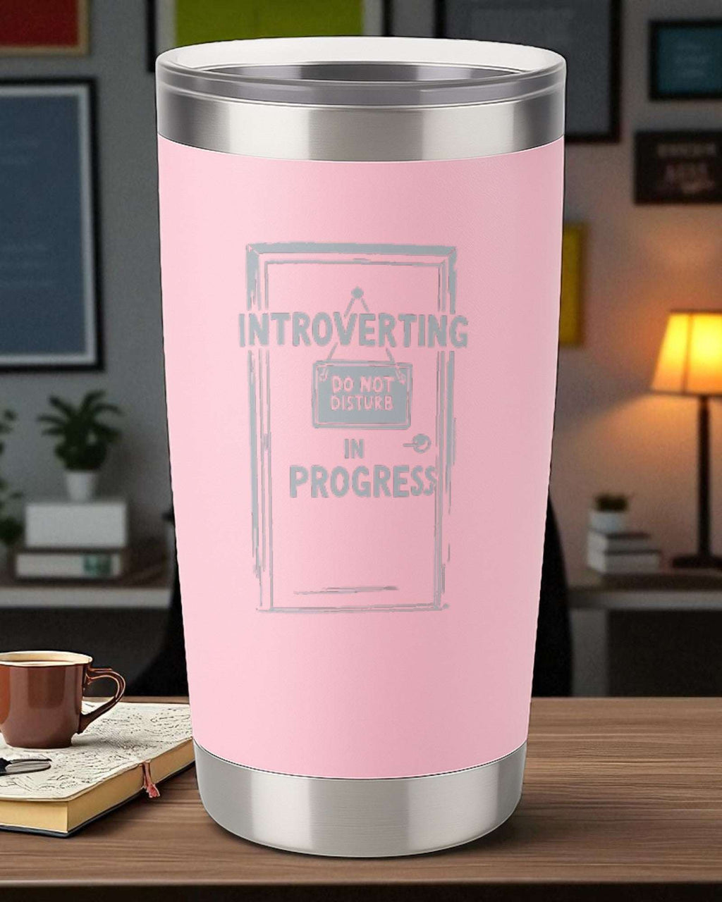 20oz pink engraved stainless steel tumbler with "Introverting in Progress" design and clear lid on wooden table