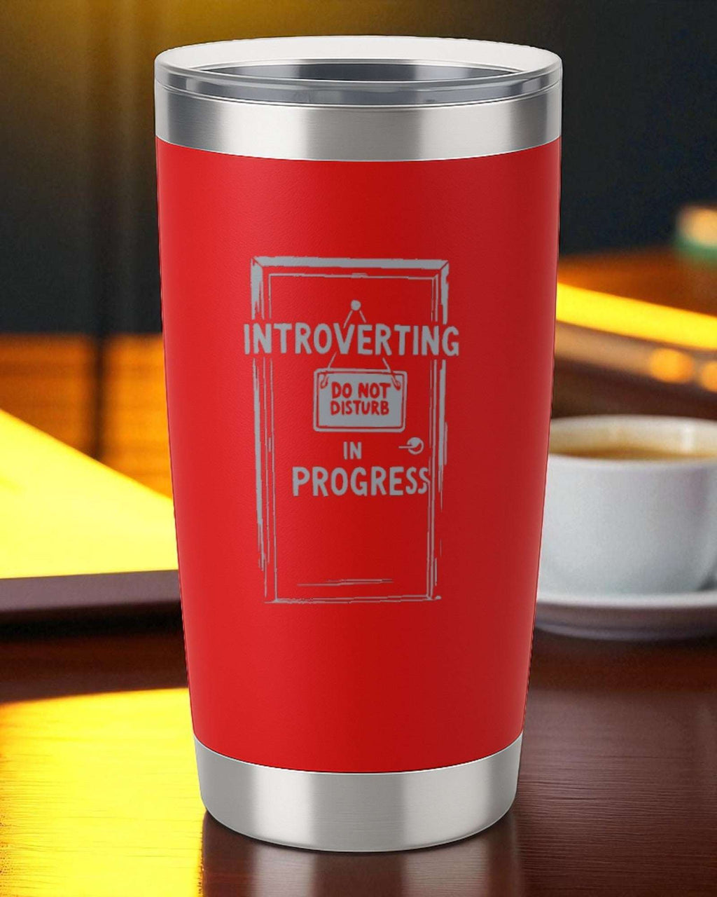 20oz red stainless steel tumbler with "Introverting in Progress" engraved design and clear slider lid on wooden table