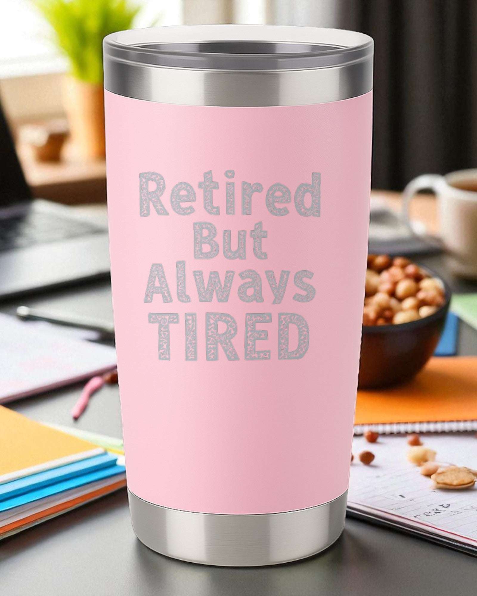 Pink 20oz stainless steel tumbler engraved with "Retired But Always Tired" text, double-wall insulated with clear slide-top lid.