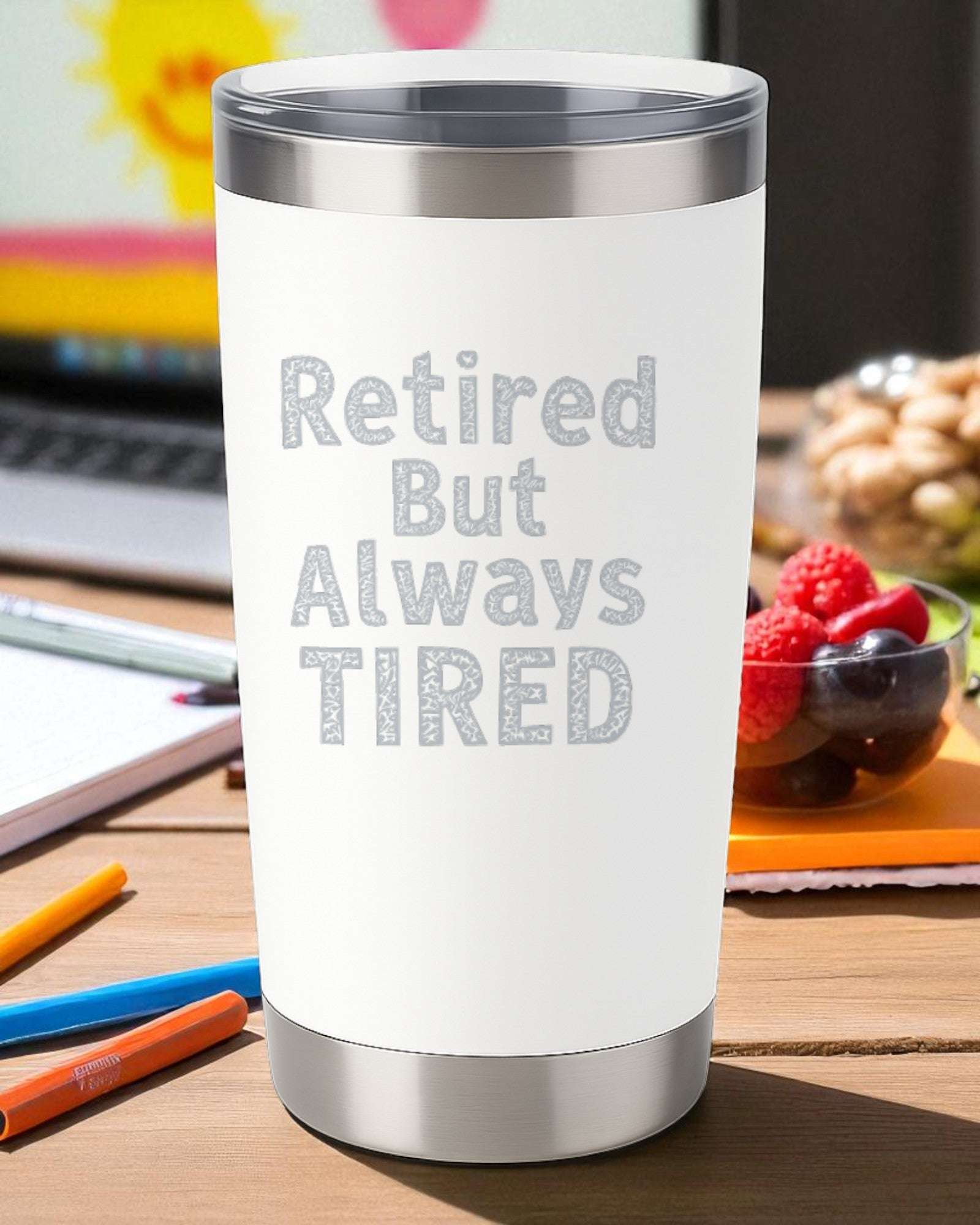 White 20oz stainless steel tumbler engraved with "Retired But Always Tired" text with double-wall insulation and clear slide lid.