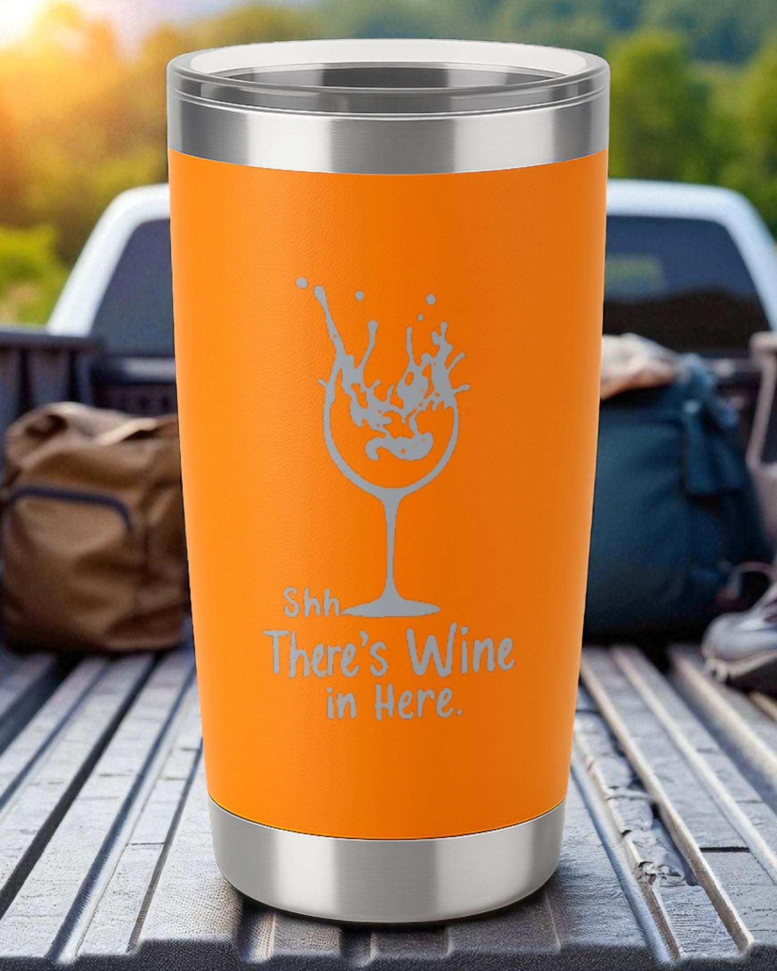 Orange 20oz stainless steel tumbler engraved with "Shhh… There’s Wine in Here" and a wine glass splash design, powder-coated and spill-resistant with clear lid.