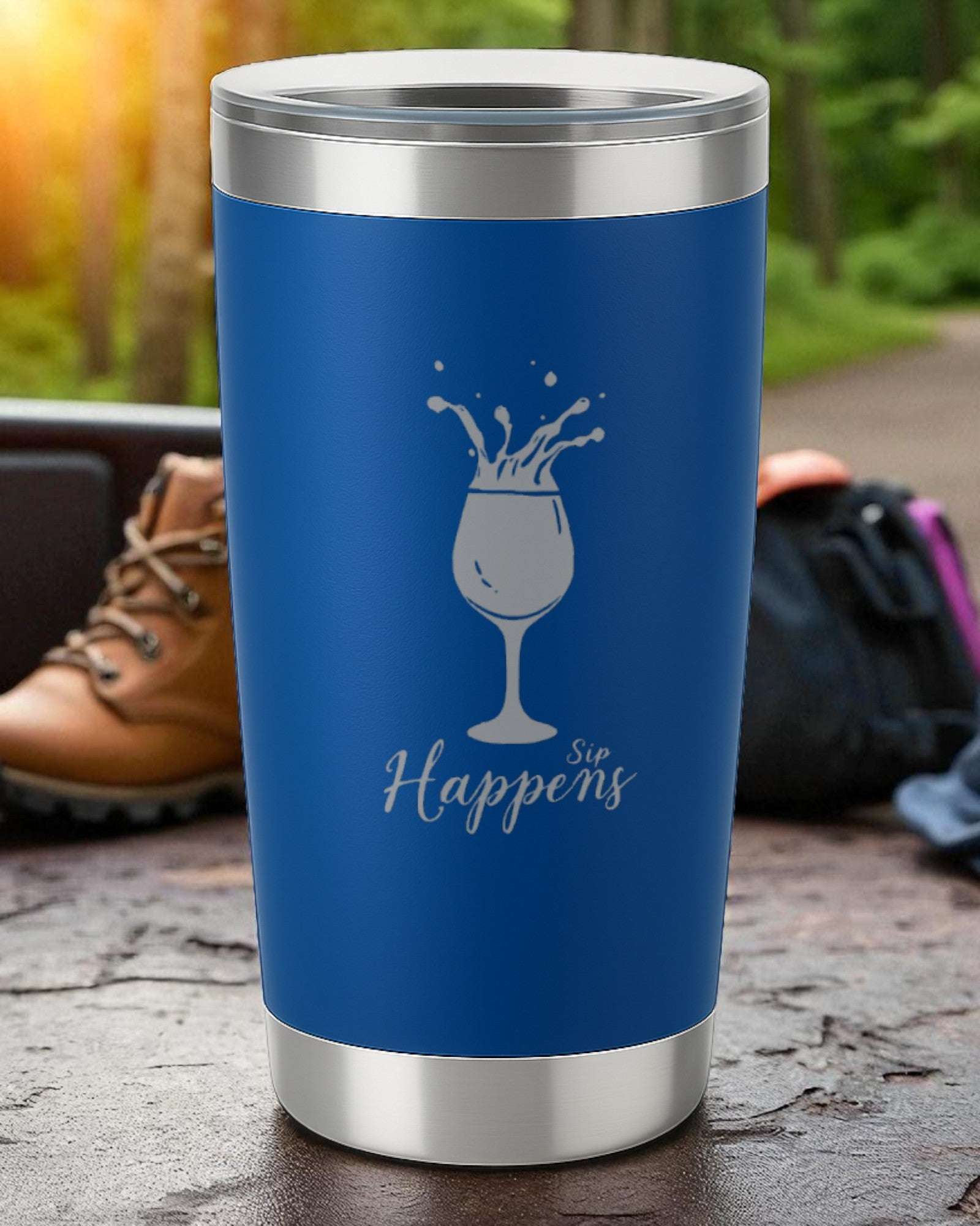 Blue 20oz insulated tumbler with silver rim and "Sip Happens" laser engraved design featuring a spilling wine glass, powder-coated finish and clear slide lid.