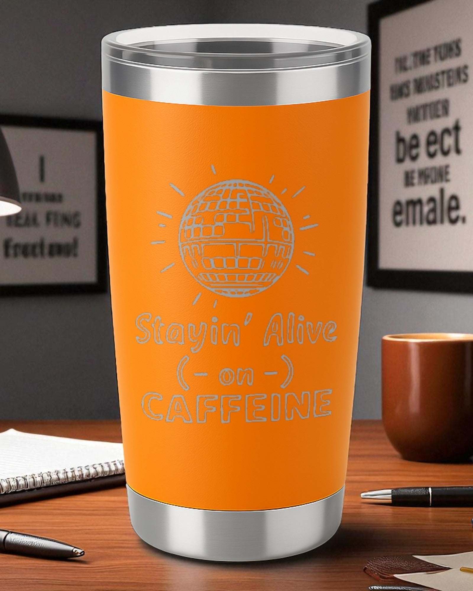 20oz orange retro coffee tumbler with laser-engraved "Stayin' Alive on Caffeine" design and clear lid on wooden desk