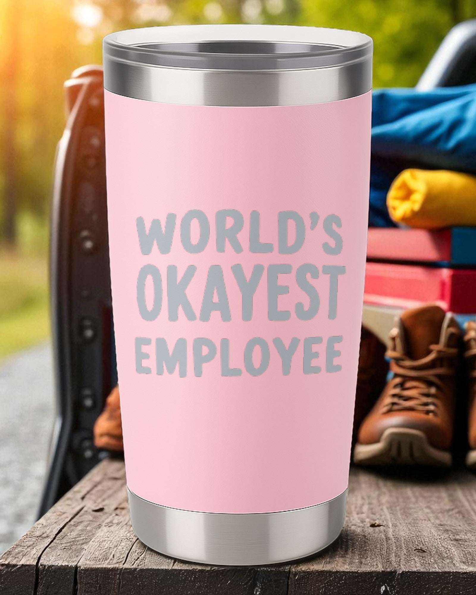 Pink 20oz stainless steel tumbler with "World's Okayest Employee" laser-engraved text and clear sliding lid.
