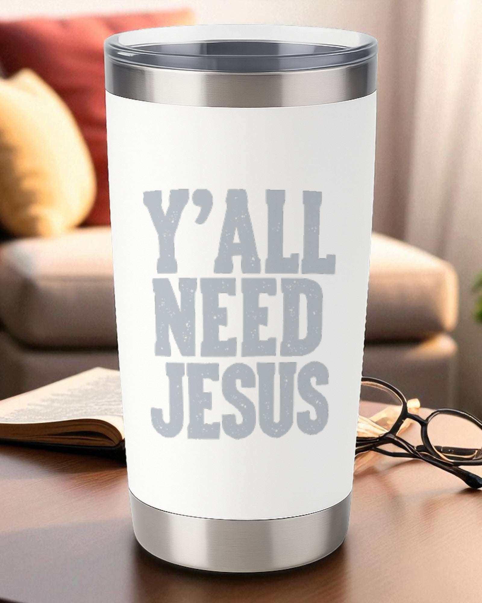 20oz white stainless steel tumbler with engraved "Y'all Need Jesus" text and clear lid on a wooden table.